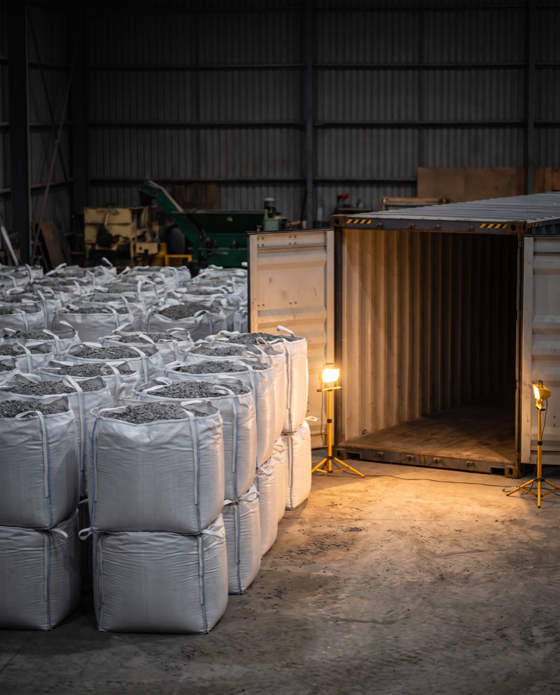 White one-tonne bags of mineral beside a shipping container