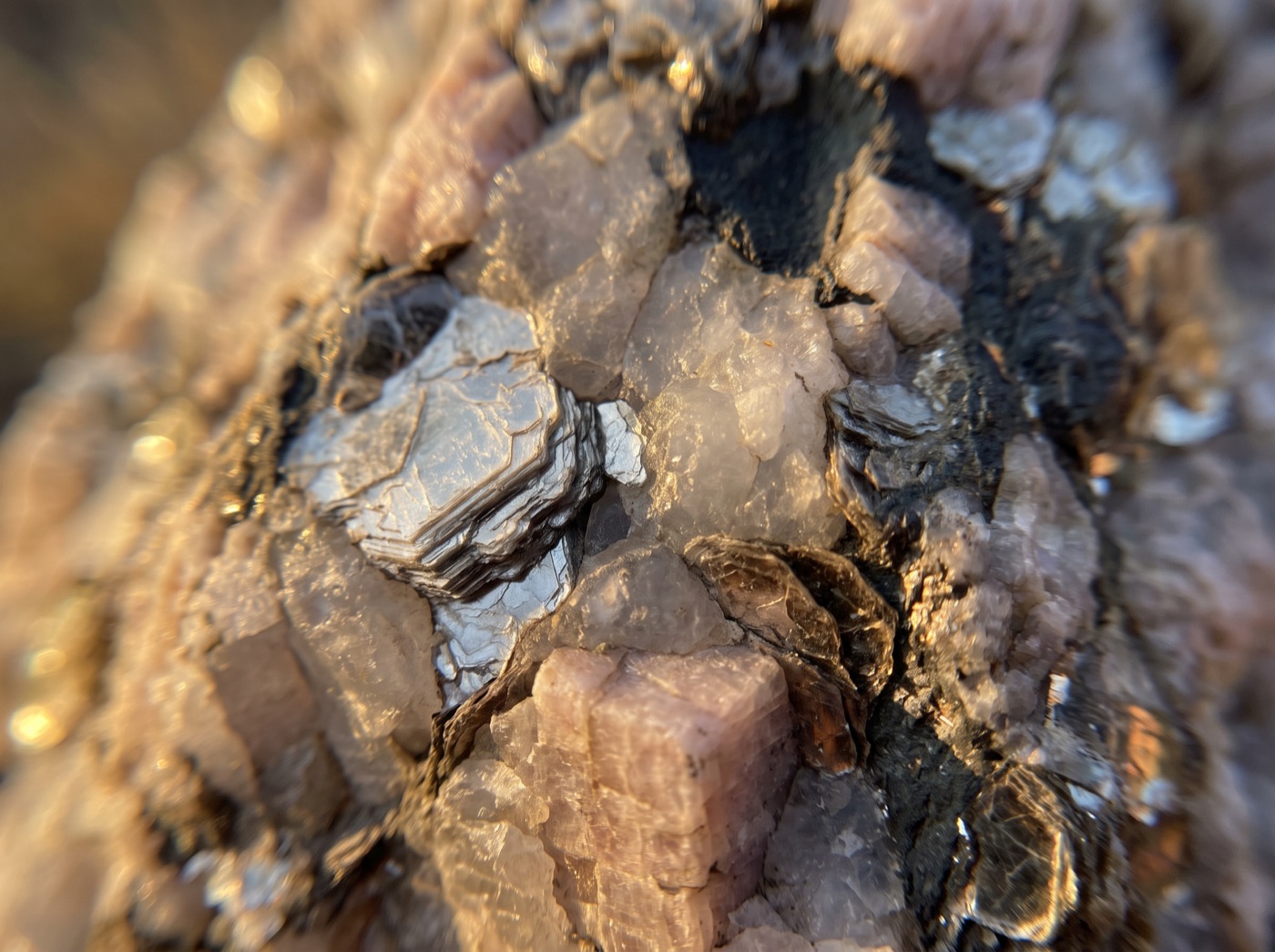 Raw mica glinting in quartz and feldspar, close up